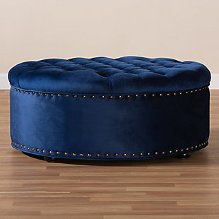 A cut above the rest, this round cocktail ottoman will exceed your expectations. This beautiful living area centerpiece is made with a sturdy wood frame, firm foam cushioning and velvet fabric upholstery. Finishing touches include nailhead trim and wood, non-marking feet.Eucalyptus wood frame | Royal blue velvet upholstery | Antiqued brass-tone nailhead trim | Black finished feet | No assembly required