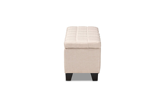 This modern ottoman displays a simple, streamlined design that makes it complementary to a wide range of decor styles. Upholstered in a soft, neutral fabric, the lid is foam padded and biscuit tufted to provide the utmost comfort. The ottoman features a large compartment under the lid, providing space to store extra blankets and pillows. Finished wood feet complete the look. Versatile enough to use as both seating and storage in the entryway, living room or bedroom.Beige polyester upholstery | Lift-top storage compartment | Wood feet with black finish | Assembly required