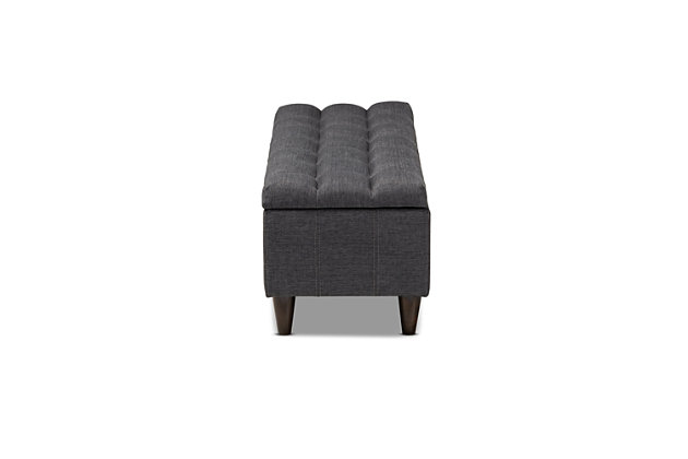 This chic ottoman features a streamlined design that makes it easy to coordinate with a wide range of decor styles. Upholstered in a soft, durable polyester fabric, the lid is foam padded and biscuit tufted to provide the utmost comfort. A compartment under the lid provides space to store extra blankets and pillows, while the tapered wood legs add mid-century modern appeal. Use this versatile piece in the entryway, living room or bedroom.Gray/beige polyester upholstery | Lift-top storage compartment | Wood legs with dark brown finish | Assembly required