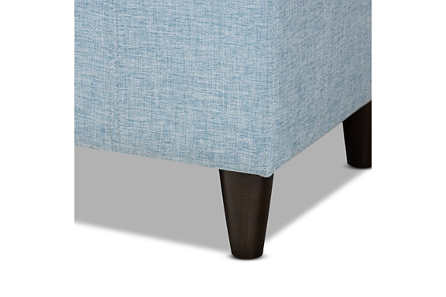 This chic ottoman features a streamlined design that makes it easy to coordinate with a wide range of decor styles. Upholstered in a soft, durable polyester fabric, the lid is foam padded and biscuit tufted to provide the utmost comfort. A large compartment under the lid provides space to store extra blankets and pillows, while the tapered wood legs add mid-century modern appeal. Use this versatile piece in the entryway, living room or bedroom.Light blue polyester upholstery | Lift-top storage compartment | Wood legs with dark brown finish | Assembly required