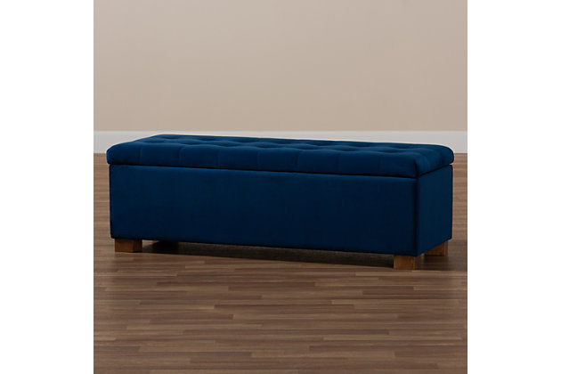 Perfect as a bed end bench for your bedroom or as an accent piece in your living space, the Roanoke storage bench combines handy seating and storage in a stylish way. Constructed with rubberwood, the bench features a cushioned seat upholstered in a soft blue velvet fabric that adds a dose of glamour to your space. The elegant grid-tufted top opens to reveal ample storage space, while walnut brown legs create a strong foundation.Contemporary style | Walnut brown legs | Made of rubberwood, engineered wood, polyester and foam | Upholstered in blue velvet polyester fabric; foam padding | Lift-top storage compartment | Imported | Requires leg assembly
