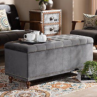 Whether it's placed in the bedroom or living room, the versatile Kaylee bench offers elegant style and handy storage space. Constructed with rubberwood, this storage bench is upholstered in a soft gray velvet fabric that adds a dose of glamour to your space. The top is padded with foam for seating comfort, and opens to reveal ample storage space for extra blankets and linens. Silvertone nailhead trim and grid stitching lend a modern look, while button tufting and turned feet add a refined elegance.Contemporary style | Walnut brown legs | Made of rubberwood, engineered wood, polyester and foam | Upholstered in gray velvet polyester fabric; foam padding | Lift-top storage compartment | Imported | Requires leg assembly