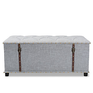 An ottoman, coffee table and storage trunk all in one, the Kyra storage ottoman adds versatility to any space. Set on top of black tapered feet, this ottoman is upholstered in an elegant linen-like fabric and features a cushioned lift-top seat that reveals ample storage space. Inspired by vintage steamer trunks, this ottoman is accented with faux leather straps and brass-tone latches. Goldtone nailheads and button tufting add an extra dose of style.Made of engineered wood and metal | Upholstered in velvet polyester fabric; foam padding | Goldtone nailhead trim; button tufting | Imported | Arrives fully assembled