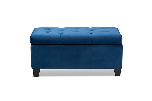 Cute, sturdy, and practical, the Michaela storage ottoman can meet a wide range of your organization needs. The modern and contemporary-inspired design emphasizes a simple silhouette and luxurious texture. The ottoman is upholstered in a rich velvet fabric, with a foam-padded, button-tufted lid. Ample storage space is located beneath the lid, made secure with a spring hinge. Black finished polymer feet complete the look. Use this ottoman as a decorative piece at the edge of a bed, as storage in the guest room, or as storage for shoes and toys in your entryway. The Michaela storage ottoman is made in China and requires assembly.Contemporary style | Made of oak wood and polymer | Upholstered in blue velvet polyester fabric; foam padding | Lift-up storage compartment | Black wooden feet | Imported | Assembly required
