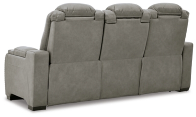 Reserved for him and made for her, The Man-Den power reclining sofa in gray delivers all the comfort and style you could ask for. Inspired by sports car interiors, the seating area is covered in real leather for your pleasure, with a “perforated automotive” treatment for that much more appeal. Positioned at your fingertips, the advanced one-touch power control puts you in the driver’s seat with everything from an Easy View™ power headrest and power lumbar support, to a USB port and wireless charging for your phone. Talk about fully loaded. The middle seat reveals a pull-down table with dimmable reading lights and cup holders. And with integrated cup holders and hidden storage compartments under the posh, padded armrests, this designer power reclining sofa makes the most of every inch of space.Dual-sided recliner | One-touch power control with Easy View™ power adjustable headrest, power lumbar support, USB charging and wireless phone charging | Wireless charger accommodates later model smartphones, including Apple iPhone, Samsung Galaxy, Huawei Mate and Nokia Lumia | Corner-blocked frame with metal reinforced seat | Attached cushions | 43" high back | High-resiliency foam cushions wrapped in thick poly fiber | Leather interior upholstery (with perforated details); vinyl/polyester exterior upholstery | Pull-down table with 2 cup holders (with 2 layers to accommodate drink containers) dimmable reading lights and magazine storage | Each armrest includes storage compartment | Extended ottoman for enhanced comfort | Nailhead trim | Power cord included; UL Listed | Estimated Assembly Time: 15 Minutes