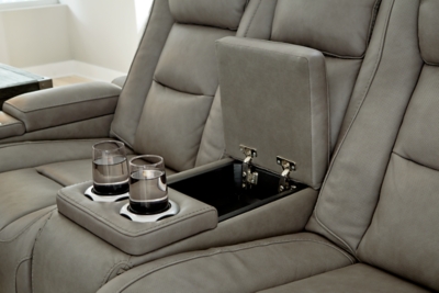 Reserved for him and made for her, The Man-Den power reclining loveseat in gray delivers all the comfort and style you could ask for. Inspired by sports car interiors, the seating area is covered in real leather for your pleasure, with a “perforated automotive” treatment for that much more appeal. Positioned at your fingertips, the advanced one-touch power control puts you in the driver’s seat with everything from an Easy View™ power headrest and power lumbar support, to a USB port and wireless charging for your phone. Talk about fully loaded. And with integrated cup holders and hidden storage compartments under the posh, padded armrests, this designer power reclining loveseat makes the most of every inch of space.Dual-sided recliner | One-touch power control with Easy View™ power adjustable headrest, power lumbar support, USB charging and wireless phone charging | Wireless charger accommodates later model smartphones, including Apple iPhone, Samsung Galaxy, Huawei Mate and Nokia Lumia | Corner-blocked frame with metal reinforced seat | Attached cushions | 43" high back | High-resiliency foam cushions wrapped in thick poly fiber | Leather interior upholstery (with perforated details); vinyl/polyester exterior upholstery | Storage console with 2 cup holders (with 2 layers to accommodate drink containers) | Each armrest includes storage compartment | Extended ottoman for enhanced comfort | Nailhead trim | Power cord included; UL Listed | Estimated Assembly Time: 15 Minutes