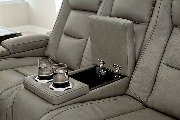 Reserved for him and made for her, The Man-Den power reclining loveseat in gray delivers all the comfort and style you could ask for. Inspired by sports car interiors, the seating area is covered in real leather for your pleasure, with a “perforated automotive” treatment for that much more appeal. Positioned at your fingertips, the advanced one-touch power control puts you in the driver’s seat with everything from an Easy View™ power headrest and power lumbar support, to a USB port and wireless charging for your phone. Talk about fully loaded. And with integrated cup holders and hidden storage compartments under the posh, padded armrests, this designer power reclining loveseat makes the most of every inch of space.Dual-sided recliner | One-touch power control with Easy View™ power adjustable headrest, power lumbar support, USB charging and wireless phone charging | Wireless charger accommodates later model smartphones, including Apple iPhone, Samsung Galaxy, Huawei Mate and Nokia Lumia | Corner-blocked frame with metal reinforced seat | Attached cushions | 43" high back | High-resiliency foam cushions wrapped in thick poly fiber | Leather interior upholstery (with perforated details); vinyl/polyester exterior upholstery | Storage console with 2 cup holders (with 2 layers to accommodate drink containers) | Each armrest includes storage compartment | Extended ottoman for enhanced comfort | Nailhead trim | Power cord included; UL Listed | Estimated Assembly Time: 15 Minutes