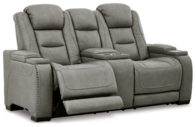 Reserved for him and made for her, The Man-Den power reclining loveseat in gray delivers all the comfort and style you could ask for. Inspired by sports car interiors, the seating area is covered in real leather for your pleasure, with a “perforated automotive” treatment for that much more appeal. Positioned at your fingertips, the advanced one-touch power control puts you in the driver’s seat with everything from an Easy View™ power headrest and power lumbar support, to a USB port and wireless charging for your phone. Talk about fully loaded. And with integrated cup holders and hidden storage compartments under the posh, padded armrests, this designer power reclining loveseat makes the most of every inch of space.Dual-sided recliner | One-touch power control with Easy View™ power adjustable headrest, power lumbar support, USB charging and wireless phone charging | Wireless charger accommodates later model smartphones, including Apple iPhone, Samsung Galaxy, Huawei Mate and Nokia Lumia | Corner-blocked frame with metal reinforced seat | Attached cushions | 43" high back | High-resiliency foam cushions wrapped in thick poly fiber | Leather interior upholstery (with perforated details); vinyl/polyester exterior upholstery | Storage console with 2 cup holders (with 2 layers to accommodate drink containers) | Each armrest includes storage compartment | Extended ottoman for enhanced comfort | Nailhead trim | Power cord included; UL Listed | Estimated Assembly Time: 15 Minutes