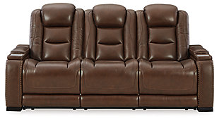 Reserved for him and made for her, this mahogany hued power reclining sofa delivers all the comfort and style you could ask for. Inspired by sports car interiors, the Man-Den power reclining sofa features real leather in the seating area for your pleasure with high-end accents for that much more appeal. The advanced one-touch power control puts you in the driver’s seat with an adjustable headrest and lumbar support, USB port and wireless charging for your phone, all at your fingertips. The pull-down table in the middle seat includes dimmable reading lights and integrated cup holders. This power recliner makes the most of every inch of space, with hidden storage compartments under the padded armrests.Dual-sided recliner | One-touch power control with Easy View™ power adjustable headrest, power lumbar support, USB charging and wireless phone charging | Wireless charger accommodates later model smartphones, including Apple iPhone, Samsung Galaxy, Huawei Mate and Nokia Lumia | Corner-blocked frame with metal reinforced seat | Attached cushions | High-resiliency foam cushions wrapped in thick poly fiber | Leather interior upholstery (with perforated details); vinyl/polyester exterior upholstery | Pull-down table with 2 cup holders, dimmable reading lights and magazine storage | 43" high back | Armrest with storage compartment | Extended ottoman for enhanced comfort | Nailhead trim | Power cord included; UL Listed | Estimated Assembly Time: 15 Minutes