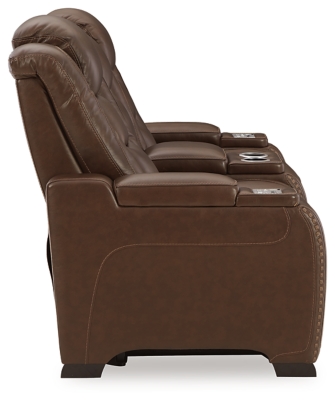 Reserved for him and made for her, this mahogany hued power reclining loveseat delivers all the comfort and style you could ask for. Inspired by sports car interiors, the Man-Den power reclining loveseat with console features real leather in the seating area for your pleasure with high-end accents for that much more appeal. The advanced one-touch power control puts you in the driver’s seat with an adjustable headrest and lumbar support, USB port and wireless charging for your phone, all at your fingertips. The center console includes two illuminated cup holders and a storage compartment. This power recliner makes the most of every inch of space, with hidden storage compartments under the padded armrests.Dual-sided recliner | One-touch power control with Easy View™ power adjustable headrest, power lumbar support, USB charging and wireless phone charging | Wireless charger accommodates later model smartphones, including Apple iPhone, Samsung Galaxy, Huawei Mate and Nokia Lumia | Corner-blocked frame with metal reinforced seat | Attached cushions | High-resiliency foam cushions wrapped in thick poly fiber | Leather interior upholstery (with perforated details); vinyl/polyester exterior upholstery | Storage console with 2 cup holders | 43" high back | Armrest with storage compartment | Extended ottoman for enhanced comfort | Nailhead trim | Power cord included; UL Listed | Estimated Assembly Time: 15 Minutes