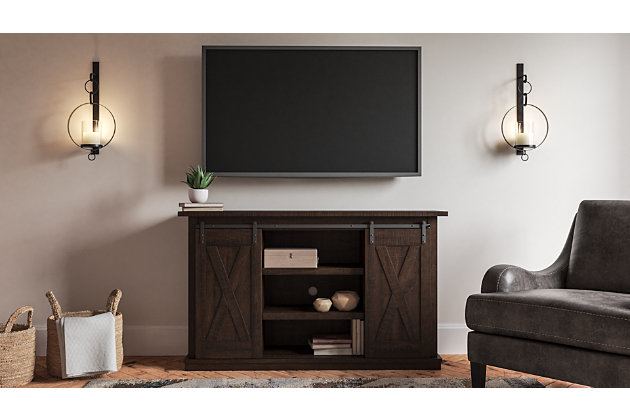 With its replicated burnt umber rustic wood grain and minimalist charm, the Camiburg TV stand is right in tune with your relaxed approach to high style. Beautifully made to accommodate your media equipment, it’s well equipped with adjustable shelving, cutouts for wire management and a sliding barn door for that modern farmhouse look you love.Made with engineered wood and decorative laminate | Replicated burnt umber rustic wood grain | 2 adjustable center shelves; 4 side shelves | Cutouts for wire management | Assembly required | Estimated Assembly Time: 45 Minutes