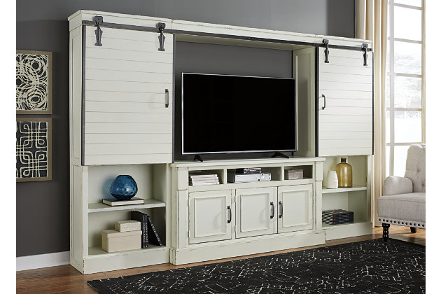 We can’t get enough of the farmhouse trend, and the Blinton entertainment center is no exception. Chipped white finish evokes an antique, time honored feel. Dark gray metal hardware creates a stark contrast that we can appreciate. Barn doors are attractive yet practical. They smoothly slide left or right in front of each pier to reveal your TV. Includes TV stand with fireplace option, bridge with sliding doors and 2 piers | Made of wood and veneers | Dark gray metal hardware | TV stand with 3 storage cubbies, 3 doors and 2 adjustable/removable shelves | Each pier includes 3 adjustable shelves and 1 fixed shelf | Fits a 60” TV | Cutouts for wire management and venting for heat | Assembly required | Estimated Assembly Time: 160 Minutes